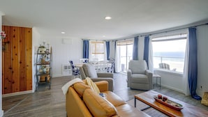 A living room with a leather sofa, a dining area with a table and chairs, and a view of the sea through large windows. - Direct Beach Access, 2 Mi to Chinook Winds Casino (Lincoln City)