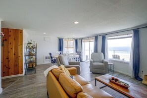 Ein Wohnzimmer mit einer Ledersofa, ein Essbereich mit Tisch und Stühlen sowie Meerblick durch große Fenster.