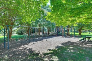 A playground with swings, slides, and climbing structures surrounded by trees. - Condo Close to Busch Gardens/colonial Williamsburg (Williamsburg)