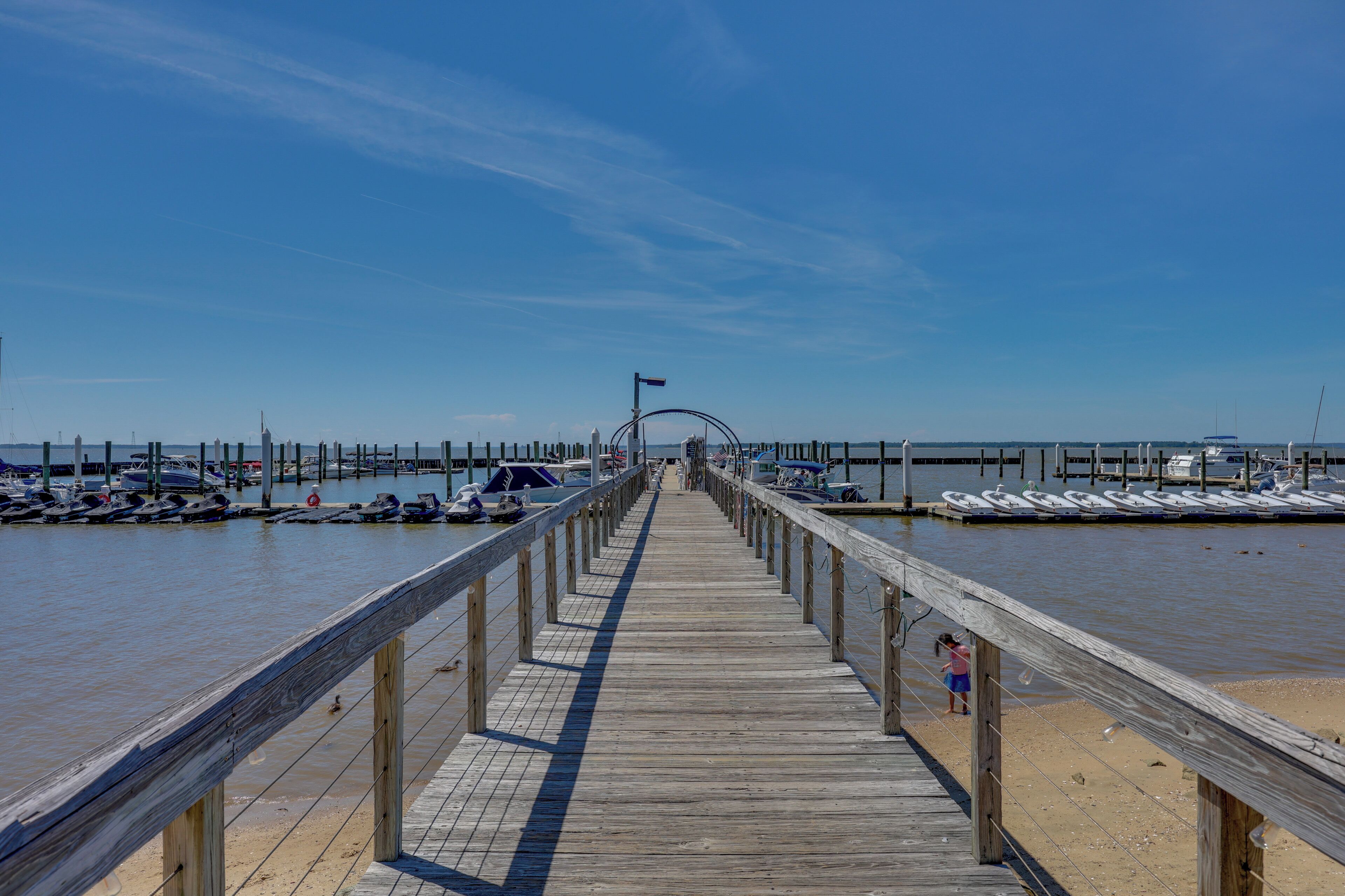 A wooden pier leading to a marina with boats docked on both sides.