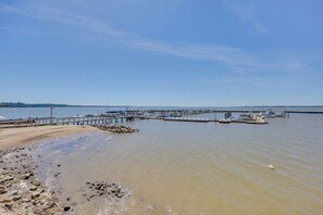 A marina with boats docked, a pier extending into the water, and a sandy beach area.