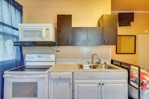 Una kitchenette compacta con microondas, estufa, pileta y alacenas.
