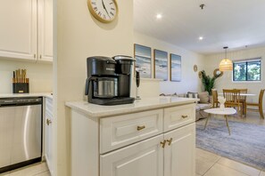 A modern kitchen with a coffee maker, a dishwasher, and a clock on the wall. - Relax, Recharge, Repeat: Hilton Head Resort Condo (Hilton Head Island)