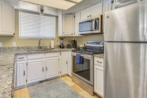 A kitchen with white cabinets, a stainless steel refrigerator, a microwave, a stove, and a coffee maker. - Centrally Located Escape in Midvale w/ Yard! (Midvale)