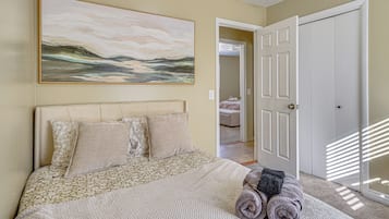 Un dormitorio con cama, un cuadro y una puerta.