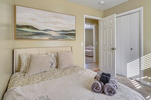 Un dormitorio con cama, un cuadro y una puerta.