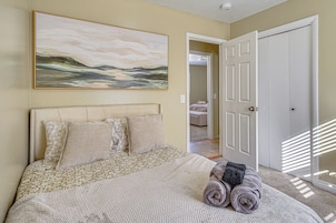 A bedroom with a bed, a painting, and a door.