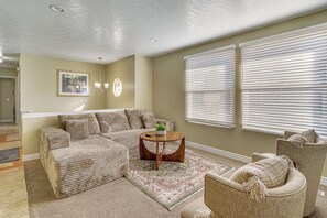 A living room with a sectional sofa, a round coffee table, and a patterned rug.