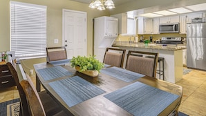 Un comedor con una mesa de madera, individuales azules y una planta en maceta.