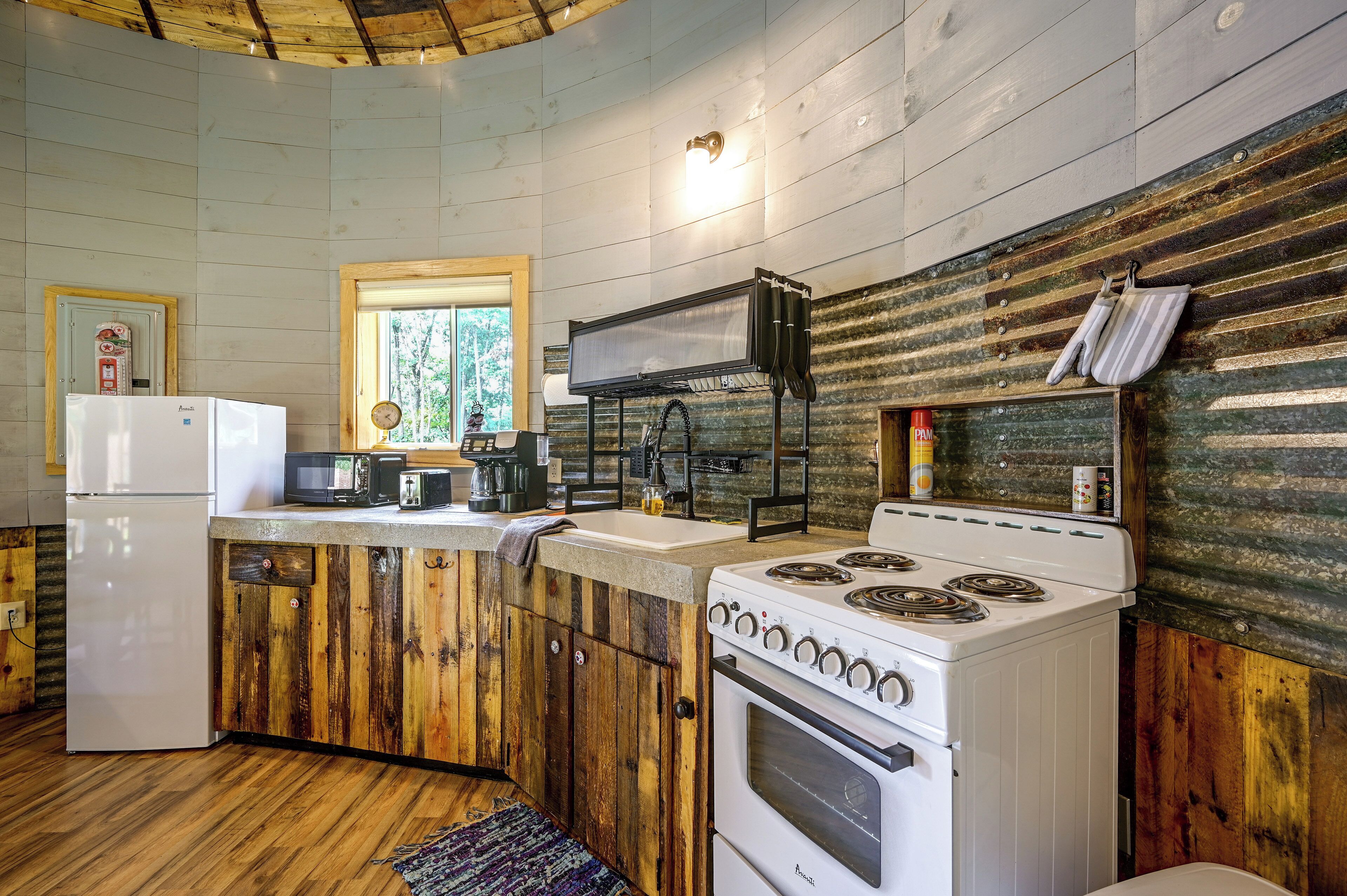A compact kitchen with a refrigerator, microwave, toaster, stove, and a window providing natural light.