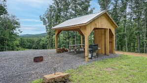 A wooden gazebo with a picnic table and grill, surrounded by a gravel area and trees. - Outdoor Oasis w/ Mtn Views! 5-acre Augusta Getaway (Augusta)