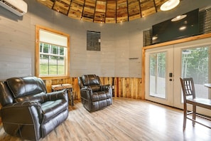 A room with a wooden ceiling, a large window, two leather sofas, a dining table with chairs, and a sliding glass door. - Outdoor Oasis w/ Mtn Views! 5-acre Augusta Getaway (Augusta)