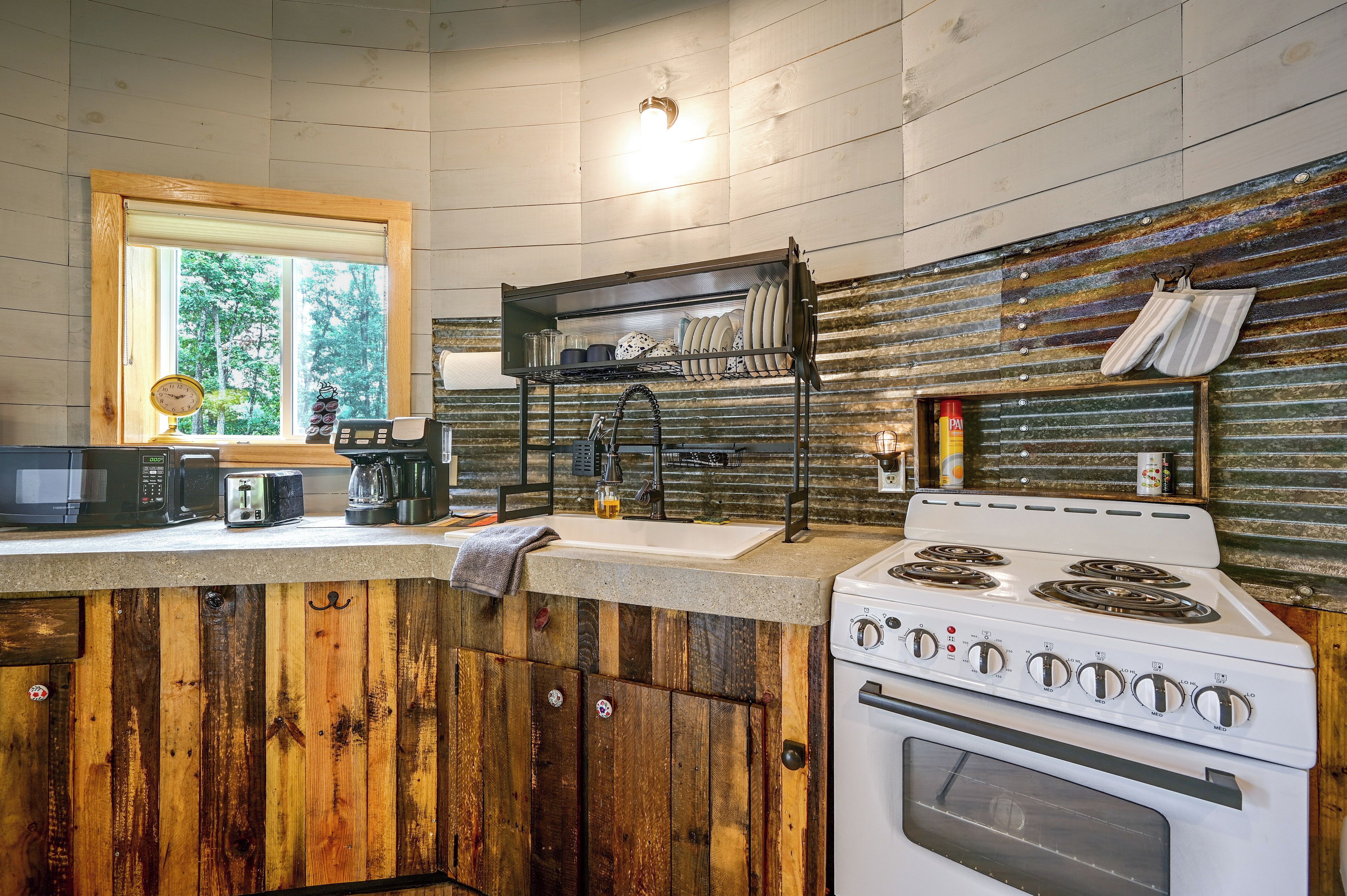 A kitchen with wooden cabinets, a stove, a microwave, and a coffee maker.