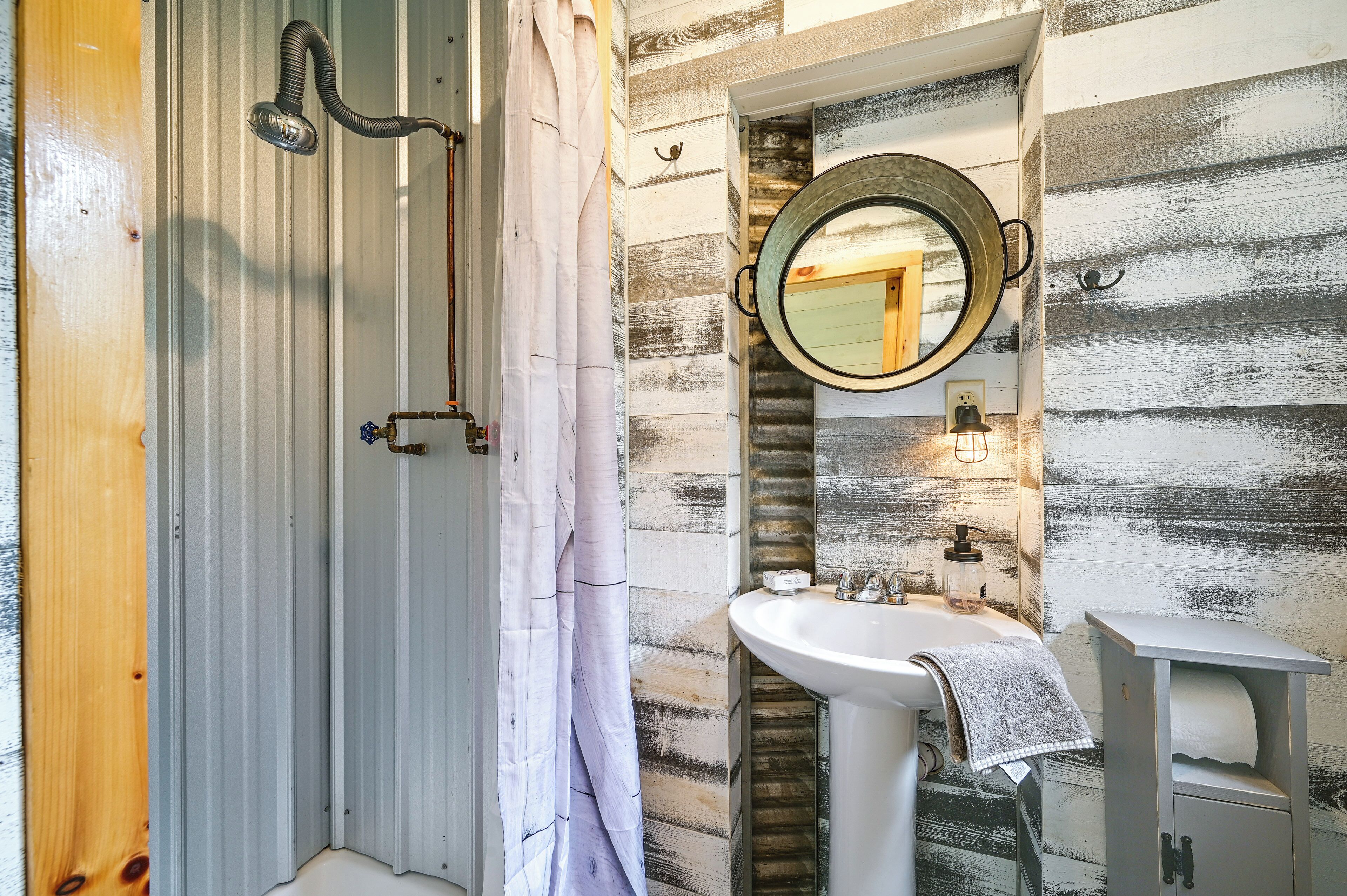 A bathroom with a shower, a sink, and a mirror.