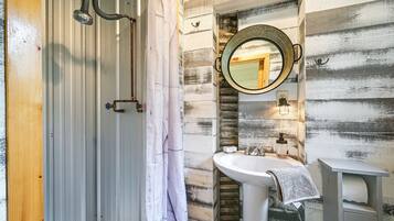 A bathroom with a shower, a sink, and a mirror.