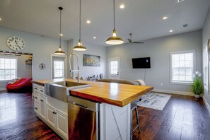 A spacious kitchen with a central island, pendant lighting, a clock, and a flat-screen TV. - Countryside Home Right Outside Fort Worth (Joshua)