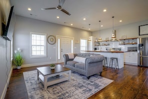 A modern kitchen with stainless steel appliances, a grey sofa, and a dining area with a wooden table and chairs. - Countryside Home Right Outside Fort Worth (Joshua)