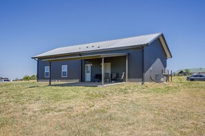 A single-story building with a covered porch, a door, and a small outdoor seating area with chairs. - Countryside Home Right Outside Fort Worth (Joshua)