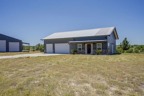 A single-story building with a garage, a covered porch, and a small front yard.