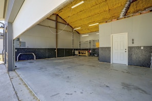 An industrial interior with a concrete floor, metal beams, and a door on the right.