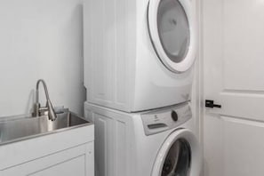 A compact laundry room with a washing machine and a sink. - Beautiful & Stylish Basement Suite in North Van! (North Vancouver)