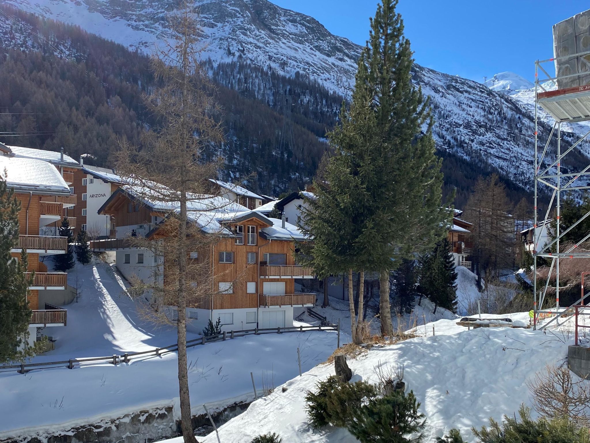 Un village de montagne enneigé, avec des bâtiments en bois et un télésiège.
