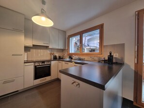 A modern kitchen with a central island, built-in oven, and a window above the sink. - Pastis Appartement/Fewo Appartement/Fewo by Interhome (Saas-Fee)