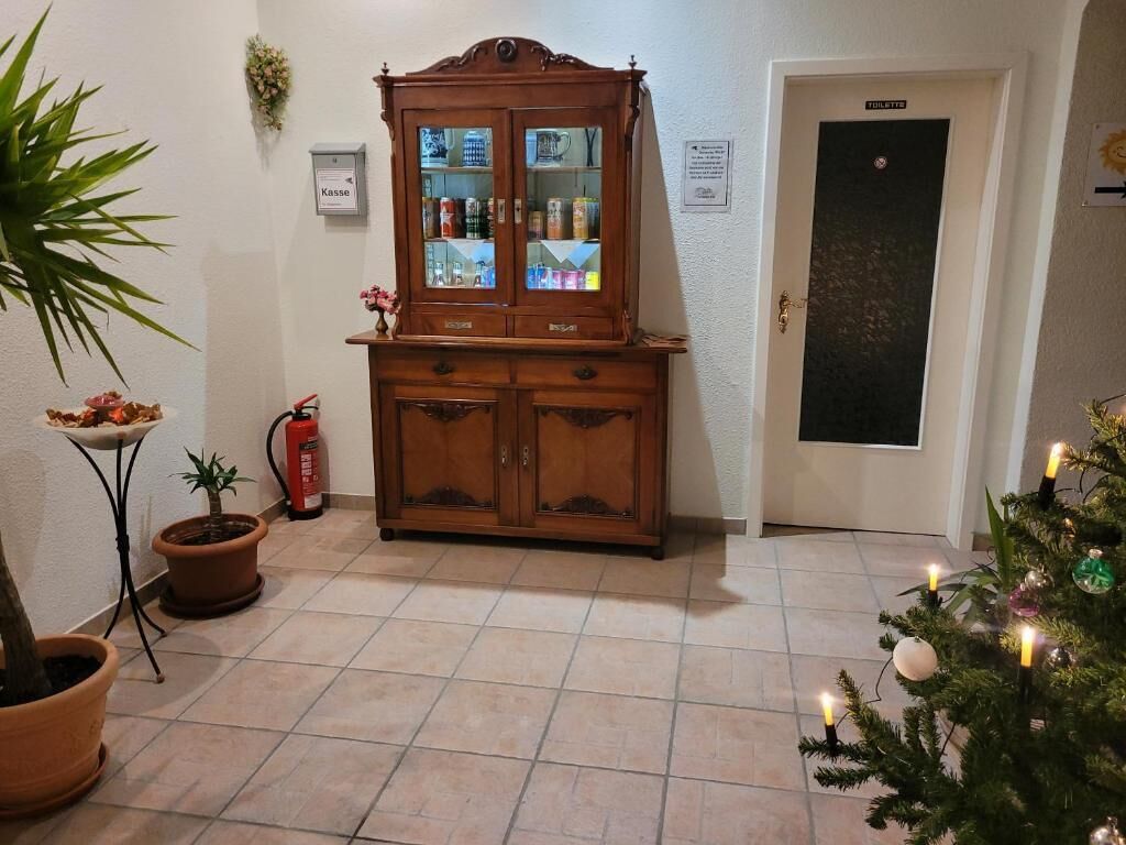 Una habitació amb un armari de fusta, una porta, un xalet de Nadal petit i una planta en test.