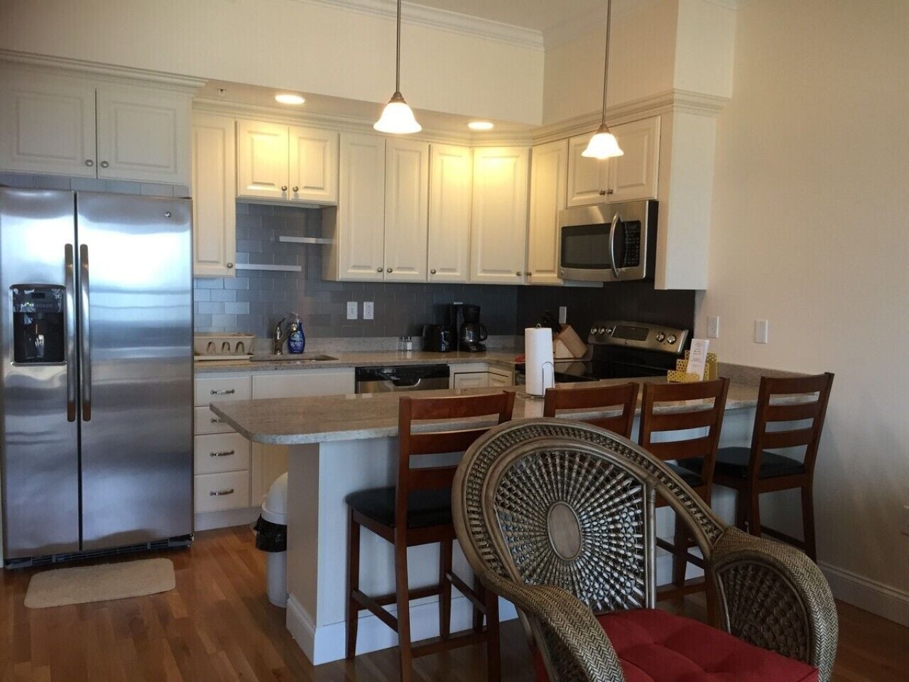 A modern kitchen with stainless steel appliances, white cabinetry, and a central island with bar stools.