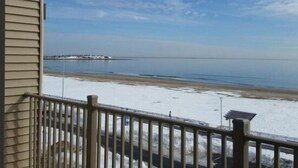 Ein Küsteneigentum mit Balkon und Meerblick, ein Steg in der Ferne sowie ein Sandstrand.