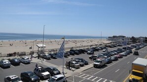 Ein Parkplatz direkt am Strand mit Autos und freiem Blick auf Strand und Meer.