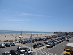 Ein Parkplatz direkt am Strand mit Autos und freiem Blick auf Strand und Meer.