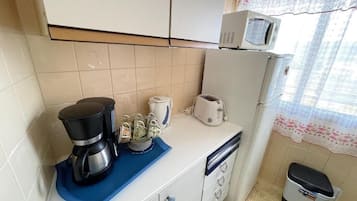 Una cocina con cafetera, tostadora y microondas en la encimera.