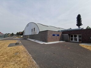 Un complex esportiu amb una àrea coberta gran i un edifici de maó.