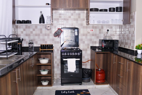 A kitchen with a stove, oven, and various kitchen utensils.
