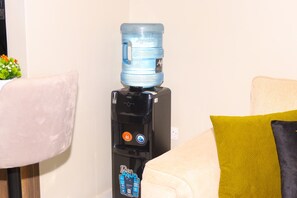 A water dispenser with a large water jug on top, a control panel with hot and cold options, and a QR code sticker.