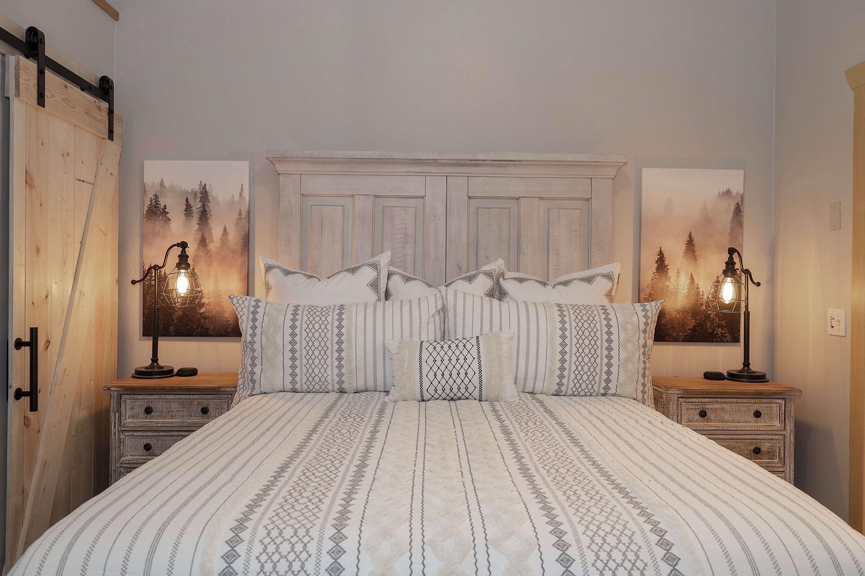 Un dormitorio con una cama grande, dos mesitas de noche, un armario de madera y dos lámparas de pared.