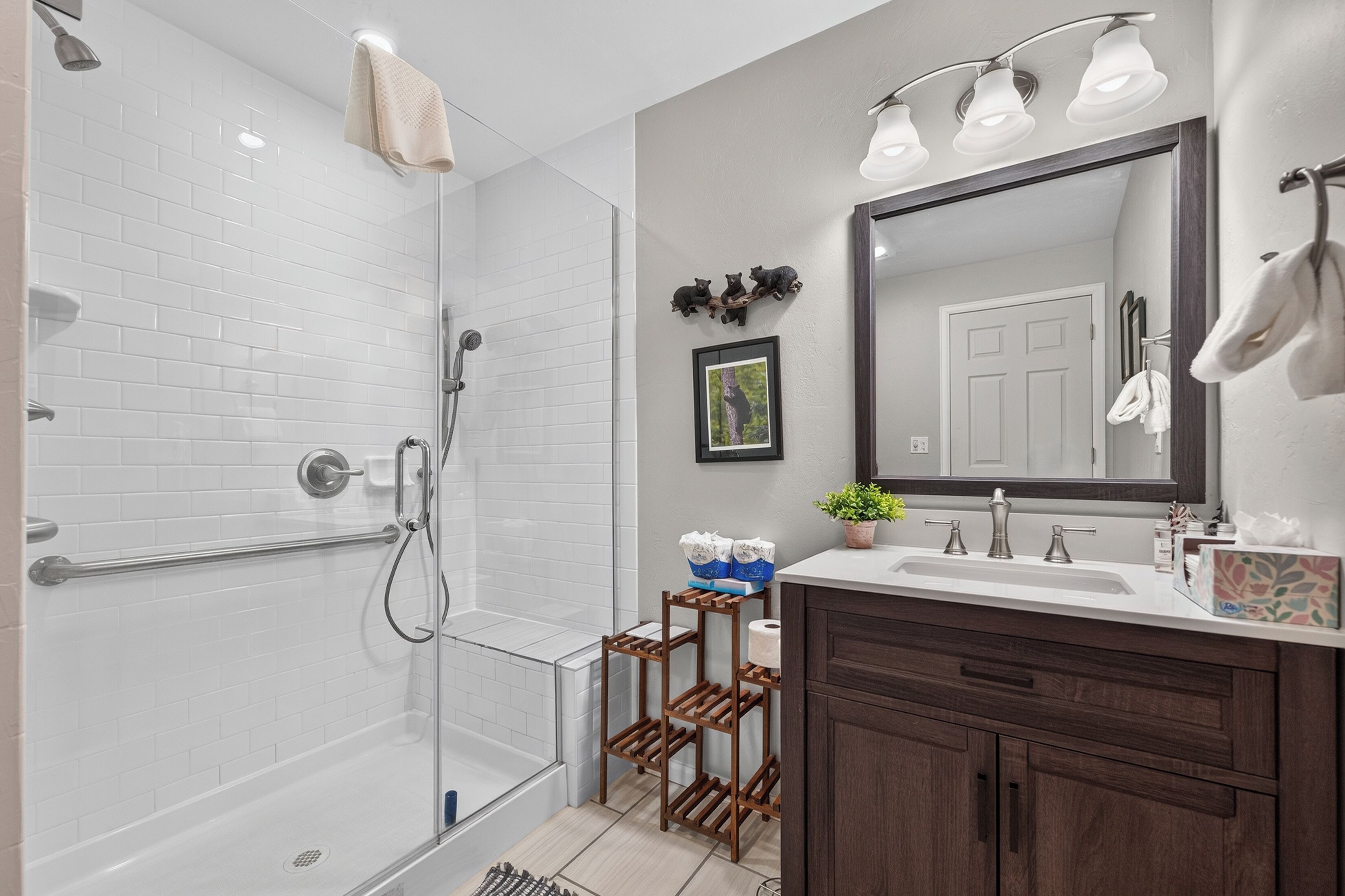 A modern bathroom with a glass shower enclosure, a vanity with a mirror, and a wooden cabinet.