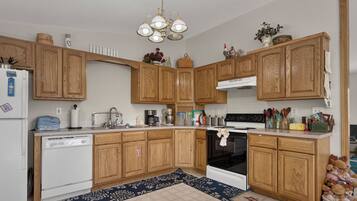 A kitchen with wooden cabinets, a dishwasher, a stove, and various kitchen appliances.