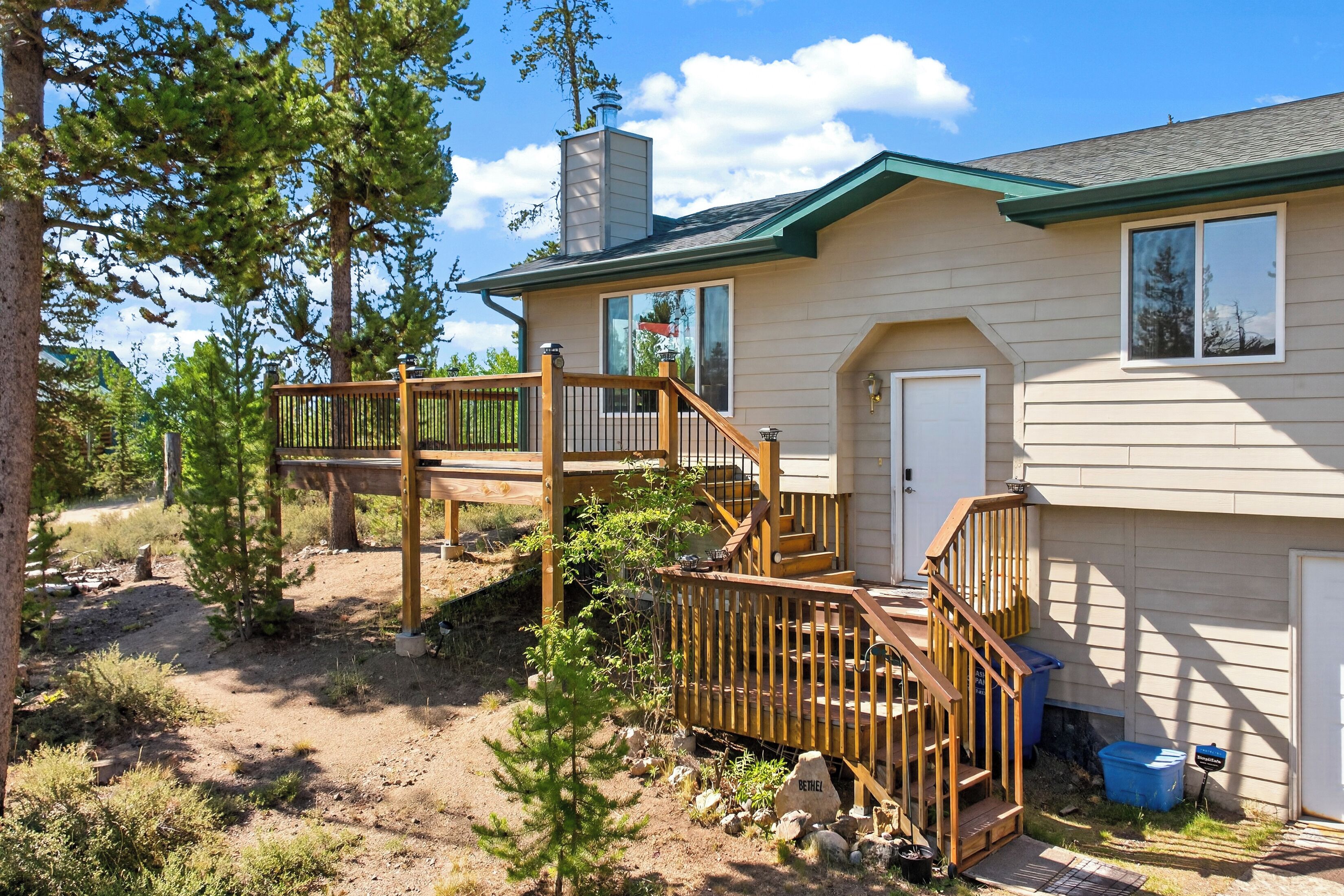 A two-story house with a wooden deck, a chimney, and a garage.