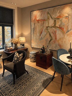 Un salon moderne agrémenté d’un grand tableau abstrait, un coin repas avec une table ronde et un espace salon confortable et accueillant.