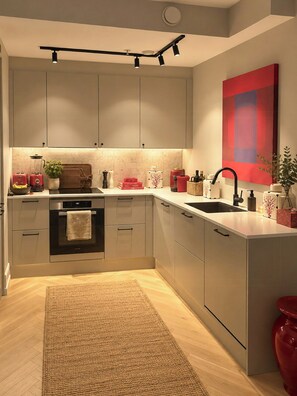 Une cuisine moderne dotée d’appareils électroménagers intégrés, d’un îlot central et d’un tableau abstrait rouge accroché au mur.