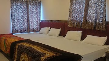 Habitación de hotel con una cama grande, dos mesitas de noche y cortinas con estampado de árboles.