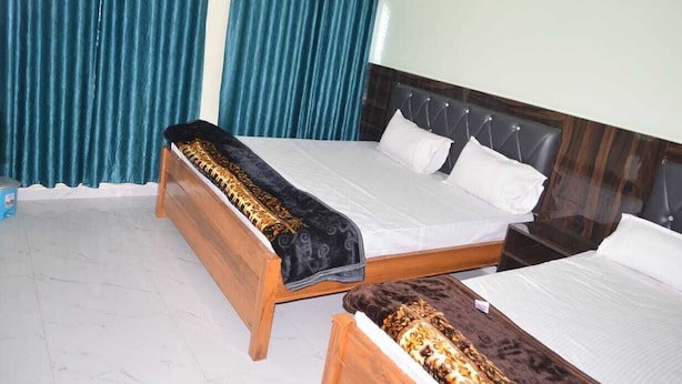 A room with two beds, a wooden headboard, a wall-mounted light fixture, and teal curtains.