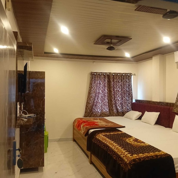 Un dormitorio con cama, televisor, ventilador de techo y ventana con cortinas.
