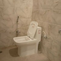 A bathroom with a toilet, a shower, and a wall-mounted bidet.
