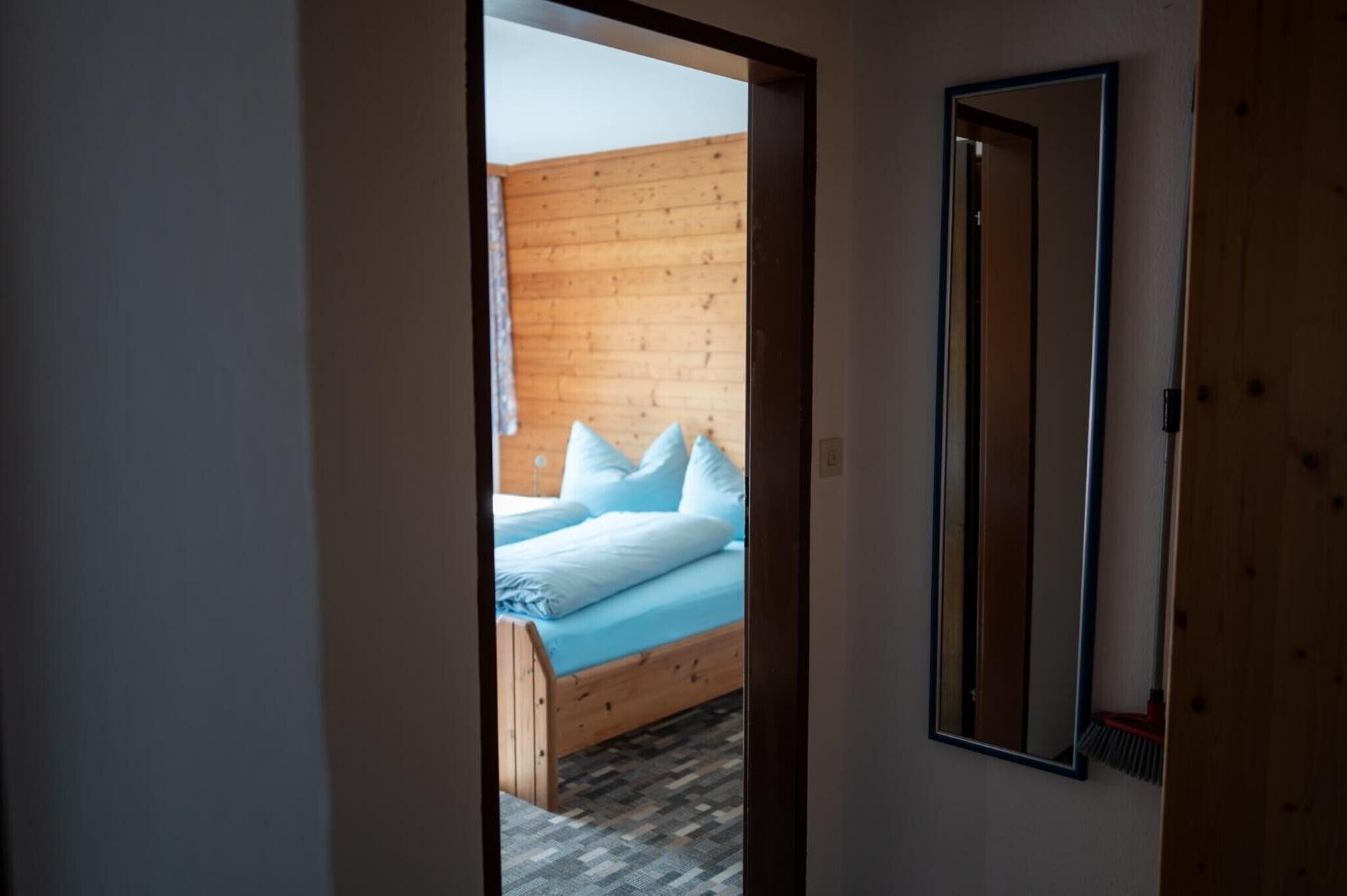 Ein Schlafzimmer mit Holz-Kopfteil, einem Bett mit weißer Bettwäsche und einem Spiegel an der Wand.