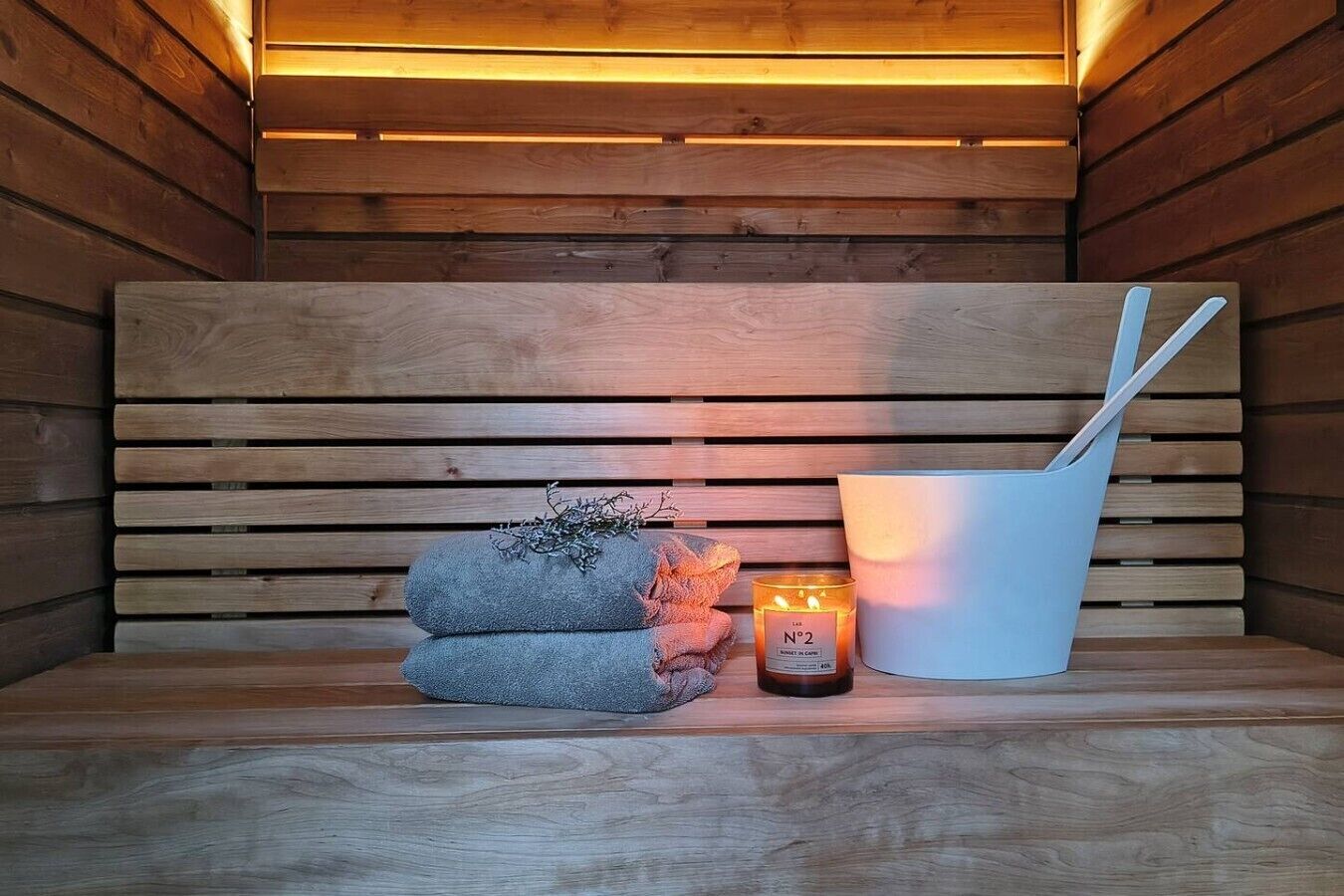 A wooden sauna bench with a towel and a candle.