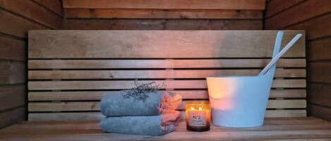 A wooden sauna bench with a towel and a candle.