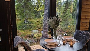 Une table dressée pour un dîner à deux, avec une bouteille de vin, des verres et un vase rempli de fleurs.